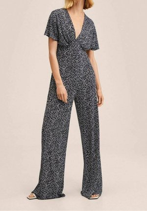 Combinaison bleu marine avec des manches courtes évasées, décolleté en V profond et motif floral blanc. Silhouette à jambes larges et texture de tissu douce.