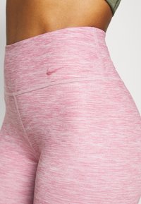 Leggings rosa alta vita realizzati in tessuto knit elasticizzato con una texture melangiata e un piccolo logo sulla cintura.