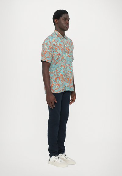 Korte mouwen overhemd in turquoise met oranje bloemenpatronen, gecombineerd met marineblauwe broek en witte sneakers. Bevat een kraag.