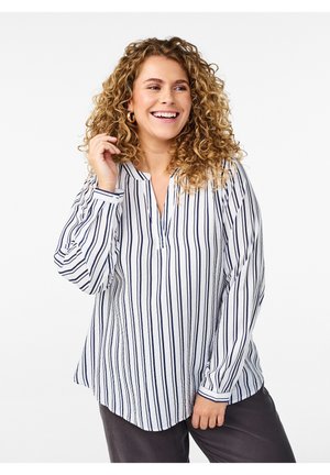 Chemise blanche à bouton avec des rayures verticales bleu marine ; elle dispose d'un col en V, de manches longues et d'une coupe décontractée. Le tissu semble léger et texturé.
