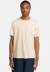 Béžové tričko s krátkym rukávom vyrobené z jemnej bavlny, s vreckom na hrudi a okrúhlym výstrihom, s pohodlným a rovnomerným strihom.