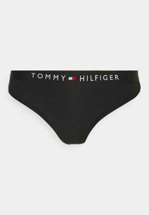 Black bikini brief made of stretchy material. Features a wide waistband with "TOMMY HILFIGER" logo in white and red. Classic design.