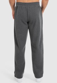 Graue Sweatpants mit entspannter Passform, elastischem Bund und subtiler Textur, ausgestattet mit Seitentaschen und geradem Bein, kombiniert mit weißen Schuhen.
