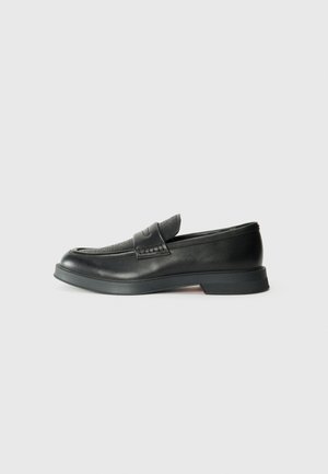 Black leather loafer with a textured upper, flat sole, and embossed accents. Features a simple design and rounded toe.