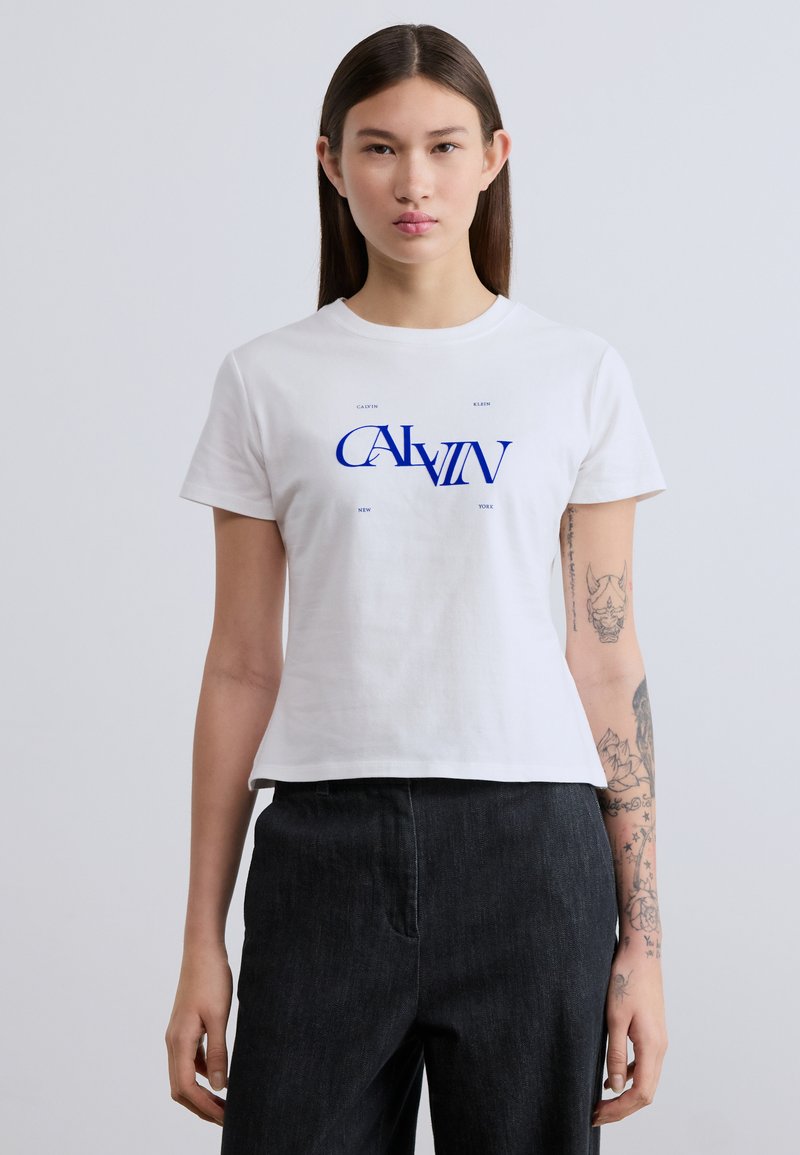 Άσπρο βαμβακερό t-shirt με μπλε γραφική εκτύπωση που γράφει «CALVIN KLEIN NEW YORK». Λαιμόκοψη crew και κοντά μανίκια, με άνετη εφαρμογή.