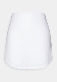 Valkoinen pellavainen minihame suoralla leikkauksella, jossa on sileä pinta, hienovaraiset ompelu-yksityiskohdat ja siisti helmaviiva.