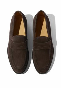 Brune ruskinds loafers med syninger, afrundet tå og en lav gummisål; glat tekstur og minimal design.