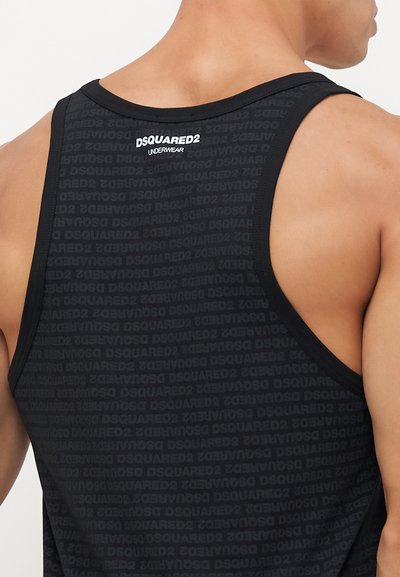 Mann in einem ärmellosen, schwarzen Dsquared2-Top, das den oberen Rücken und die Schultern zeigt, vor einem schlichten Hintergrund.