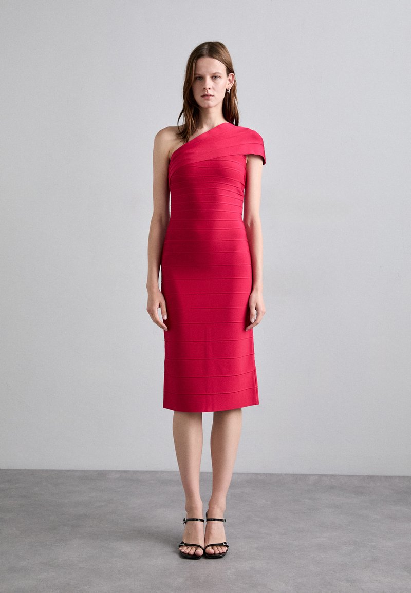 Rotes, geripptes, knielanges Kleid mit asymmetrischem Tragen. Glatte Textur, taillierte Silhouette. Getragen mit schwarzen Riemchensandalen.