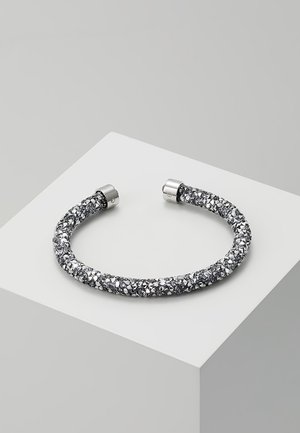 Zilverkleurige manchettenarmband met een textuur van gefragmenteerd kristalontwerp, open aan het uiteinde voor verstelbare pasvorm, tentoongesteld op een wit voetstuk.