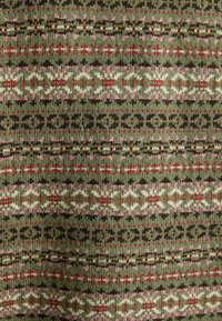 Roheline kudumise kangas, millel on horisontaalne Fair Isle muster, kus on punased, roosad, valged, pruunid ja beežid geomeetrilised kujundid ja triibud.