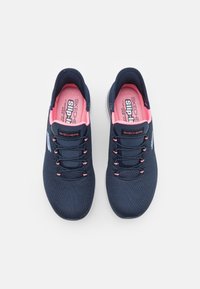 Paire de baskets Skechers bleu marine sans lacets avec doublure intérieure rose et lacets élastiques noirs, vues d'en haut sur fond blanc.