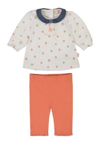 Camicia bianca a maniche lunghe con pois colorati, colletto in denim e dettagli ricamati, abbinata a pantaloni corallo alla caviglia con orlo arricciato.