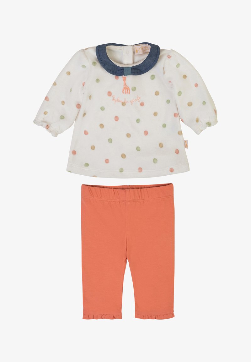 Camicia bianca a maniche lunghe con pois colorati, colletto in denim e dettagli ricamati, abbinata a pantaloni corallo alla caviglia con orlo arricciato.