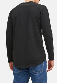 Sort langærmet t-shirt med rund hals, lige pasform og afrundet kant, parret med blå jeans. Blødt bomuldsstof.