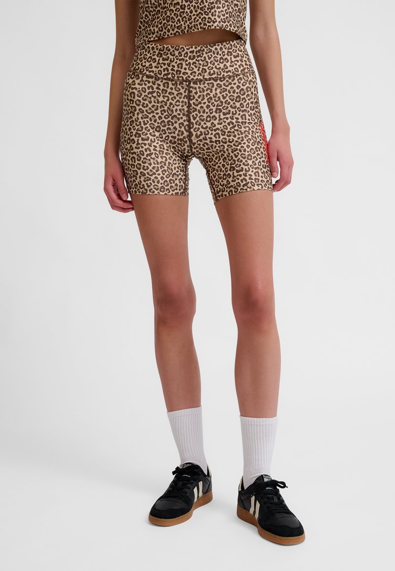 Leopardprintshorts van gladde stof, met een hoge tailleband en een aangesloten pasvorm, gecombineerd met zwarte sneakers en witte sokken.