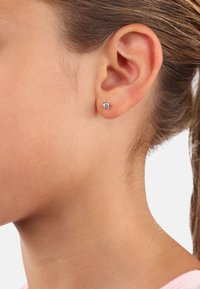 Silberne Steckerohrringe mit einem runden lila Edelstein. Der Ohrring ist klein und sitzt passend am Ohrläppchen. Die Oberfläche ist glatt und poliert.