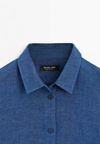 Blue linen shirt with collar and two visible black buttons, showing a black label reading "Massimo Dutti Made in Morocco".