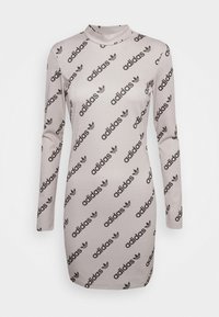 Langemouwenjurk in lichtbeige, gemaakt van glanzende stof met herhaaldelijk zwarte "adidas" logo en trefoil-patronen overal.