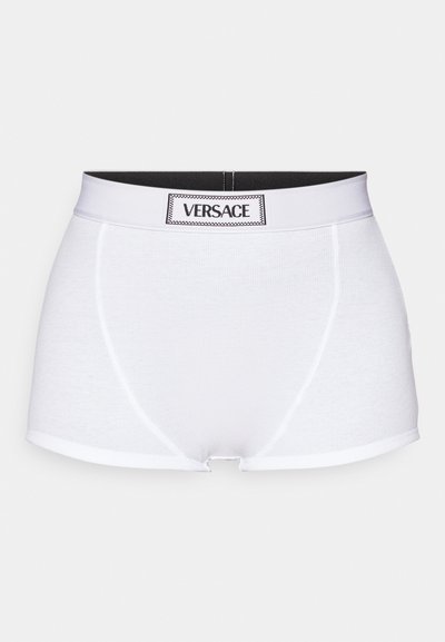 Valged puuvillased bokserid, millel on must elastne vöökoht ja "VERSACE" logo. Sile tekstuur, minimalistlik disain ja keha lähedane lõige.