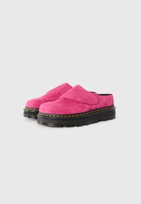 Pink suede slip-on shoes with a thick black rubber sole and yellow stitching details. Smooth texture and rounded toe design.