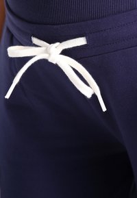 Námořnické modré tepláky s jemnou, hladkou texturou, vybavené bílým šňůrkovým páskem v pase a elastickým pasem pro bezpečné nošení.