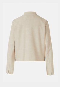 Blazer en tissu beige texturé avec manches longues, détail d'empiècement au dos et fentes latérales aux poignets, vu de dos.