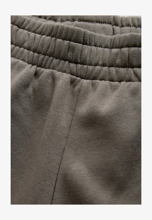 Stretchigt, mörkgrått tyg med resår i midjan och mjuk textur. Har en detaljerad söm i sidan, lämplig för vardagsbruk.