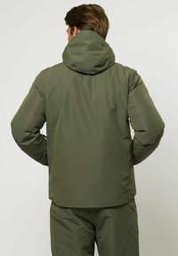 Olajzöld, könnyű dzseki kapucnival, sima textúrával és enyhén testhezálló fazonnal. A hátsó nézeten nincsenek fém részletek.