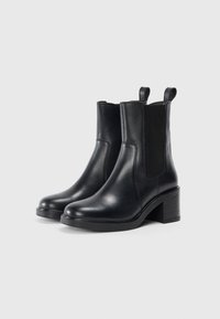 Sorte skinn ankle boots med elastiske sidepaneler, rund tå og tapered blokkhæl. Glatt tekstur og pull-tab for enkel påkledning.