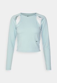 Hellblaues langärmliges Crop-Top mit rundem Ausschnitt, Auschnitt-Design an den Schultern und schwarzem Nike-Logo auf der Vorderseite. Glatte Stofftextur.