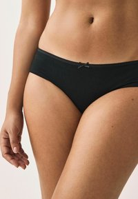 Čierne bavlnené bikiny s hladkým povrchom, čipkový lem na páse a malou mašľou vpredu.