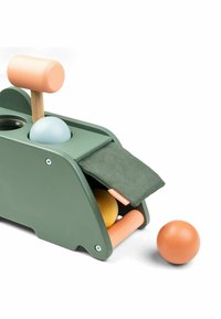 Juguete de madera con una base verde, que presenta un martillo rosa y tres bolas de colores (azul, amarillo, naranja). Incluye una bolsa de tela.