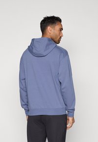 Μπλε φούτερ με κουκούλα και άνετη εφαρμογή, με τσέπη καγκουρό, ριμπ μανσέτες και τελείωμα. Απαλή υφή, με ελάχιστες ραφές.