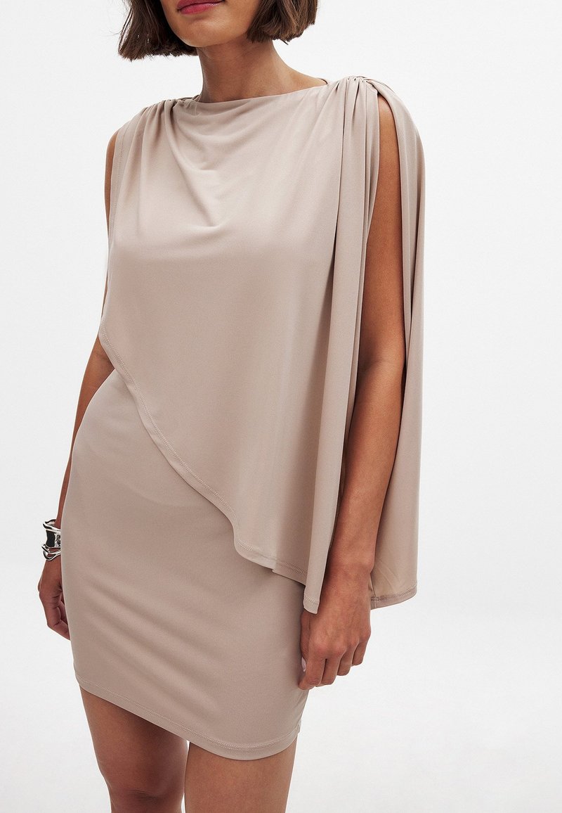 Robe couleur nude avec un décolleté drapé, un ourlet asymétrique et des manches courtes. Fabriquée dans un tissu lisse et léger.