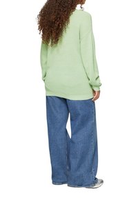 Mintgrüner, gestrickter Pullover mit lockerer Passform und gerippten Bündchen, kombiniert mit weit geschnittenen blauen Jeans. Hat einen strukturierten Stoff.