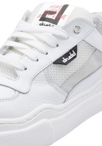 Sneaker in pelle bianca con dettagli in tessuto a rete e pannello in suede grigio. Presenta lacci piatti, collarino imbottito e logo laterale. Testo sulla linguetta.