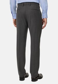 Pelēki vilnas kostīmpanti ar pielāgotu piegriezumu, jostas cilpām un divām aizmugurējām kabatām, saskaņoti ar melniem stila apaviem.