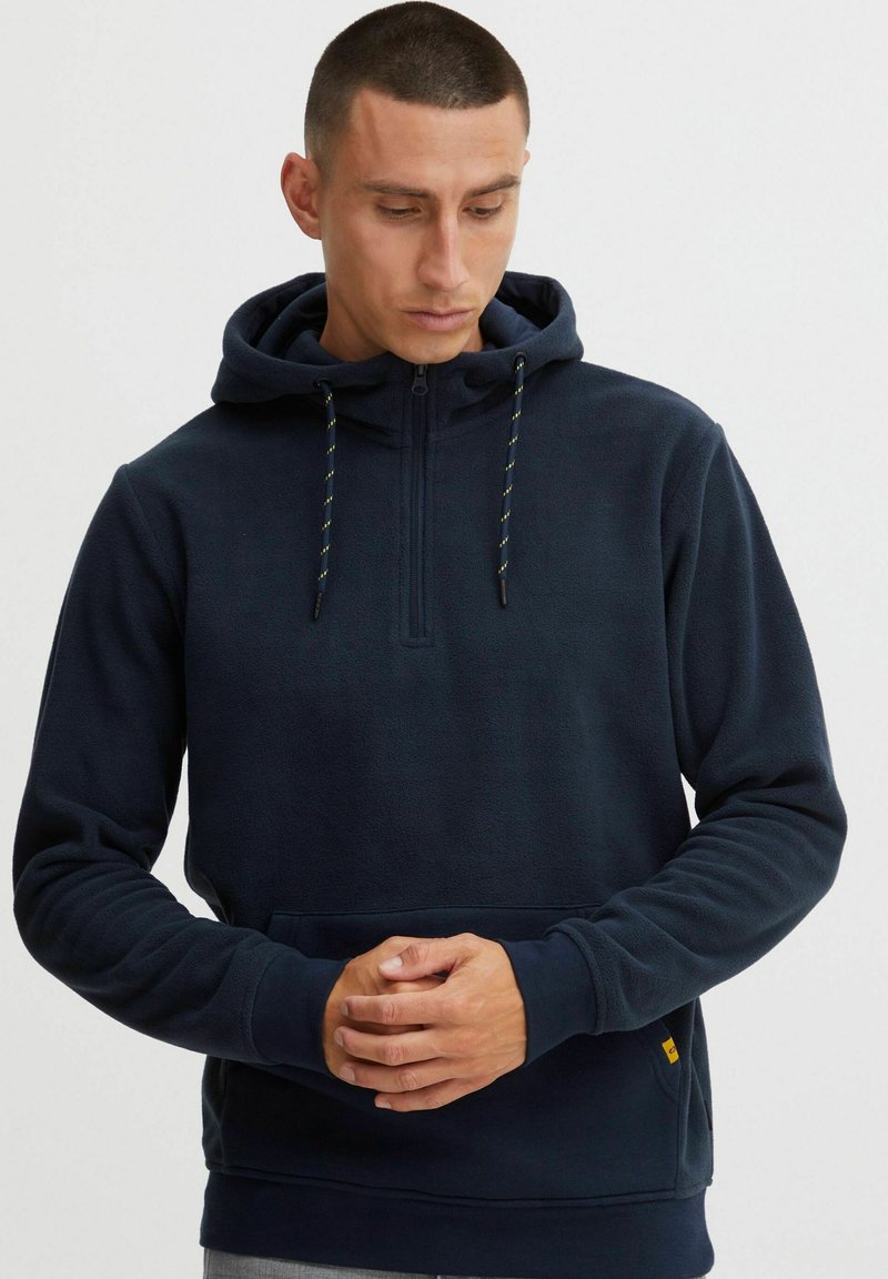 Navy fleece hoodie with a half-zip, adjustable hood, and contrasting drawstrings. Features a kangaroo pocket and ribbed cuffs.