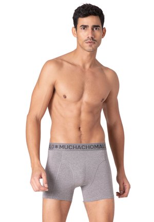 Graue Boxer-Shorts mit weicher Textur und elastischem Bund, der in dunklen Buchstaben "MUCHACHOMALO" aufgedruckt ist. Taillierte Form für zusätzlichen Komfort.