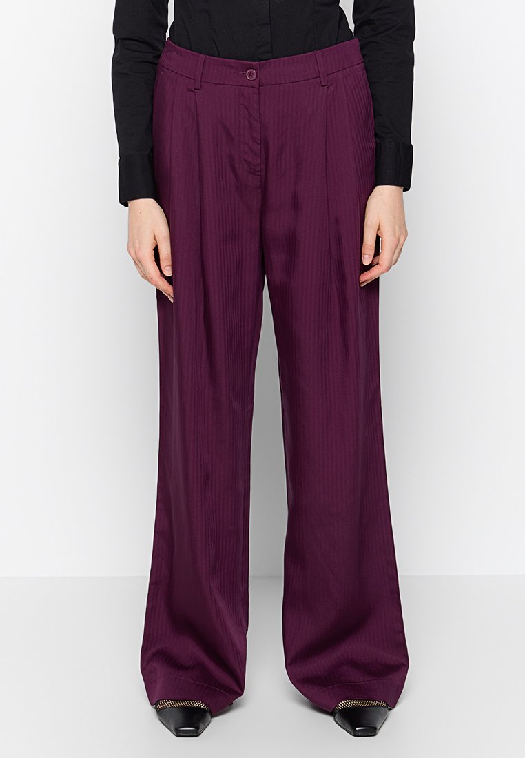 Pantalon large violet en tissu lisse avec un motif en rayures verticales. Équipé d'une fermeture à bouton et de deux poches latérales.