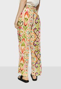 Mönstrade breda byxor med hög midja och bältesband, i flera färger med en blandning av organiska former i rosa, grön och orange nyanser.