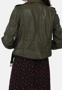 Olive green leather jacket with a fitted design, shoulder epaulets, and a smooth finish, paired with a black floral-patterned dress.