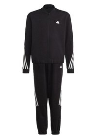 Tuta nera composto da una giacca con zip e colletto alto, con accenti bianchi a tre strisce sulle maniche, abbinato a pantaloni tapered coordinati.