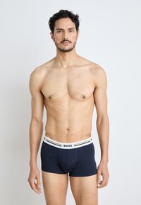Námornícke boxerky s bielym pásom s logom, na ktorom sú dve tenké pruhy. Vyrobené z hladkej tkaniny, navrhnuté pre pohodlné priliehanie.
