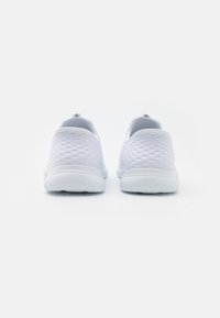White athletic shoes with a textured mesh upper, rounded toe, and cushioned sole. Smooth accents at the heel and a flexible design.