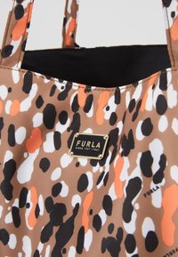 Sac fourre-tout en cuir marron avec un motif abstrait coloré en orange, noir et blanc. Comprend une plaque logo dorée avec le nom de la marque.