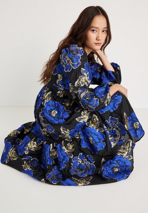 Black fabric dress featuring large blue floral embroidery with gold accents. Long sleeves and a full skirt create a flowing silhouette.
