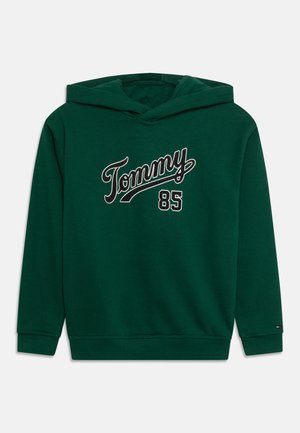Mørkegrøn hættetrøje med "Tommy"-skrift og tallet "85" i hvidt og sort på brystet, ribstrikkede manchetter og kant.