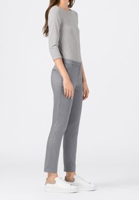 Grå randig topp med trekvartslånga ärmar och gråa figursydda byxor. Vita sneakers med beige accenter. Slät tygtextur och skräddarsydd design.